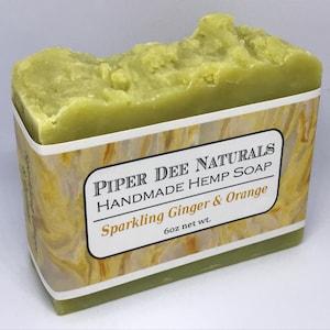 May include: A green bar of soap with a white label that reads "Piper Dee Naturals Handmade Hemp Soap Sparkling Ginger & Orange 6oz net wt."