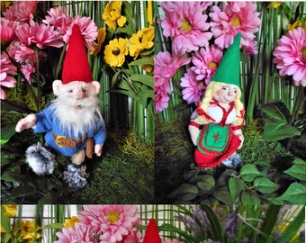 May include: Three handmade felt gnome dolls with different outfits and hats. The gnomes are sitting in a garden setting with green plants and pink flowers.