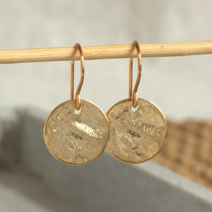 Shiny small gold earrings with an irregularly structured surface