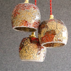 May include: Three hanging light fixtures with gold and red mosaic glass shades.