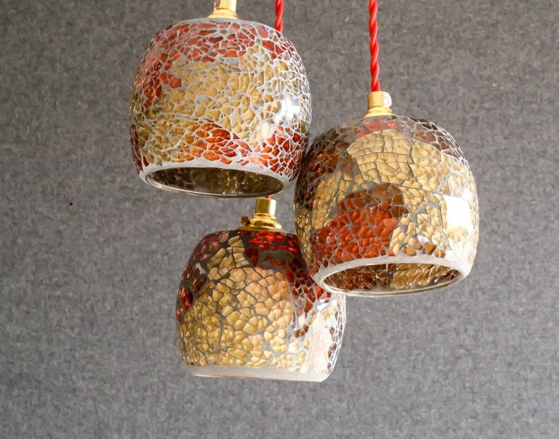 May include: Three hanging light fixtures with gold and red mosaic glass shades.