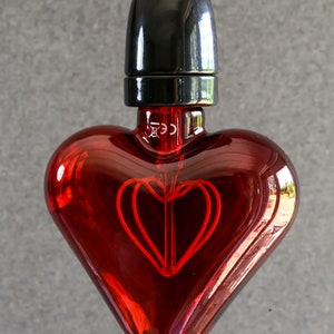 May include: A red heart-shaped light bulb with a black socket and a visible filament in the shape of a heart.