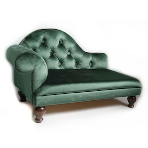 May include: A dark green velvet chaise longue featuring a tufted backrest with button detailing, a single rolled armrest on the left side, and four dark brown wooden feet. The piece has a smooth seat cushion and a curved back design.