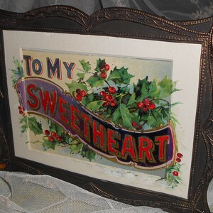 May include: A framed vintage holiday card with a gold, purple, and red banner that reads "To My Sweetheart". The banner is surrounded by holly leaves and red berries.