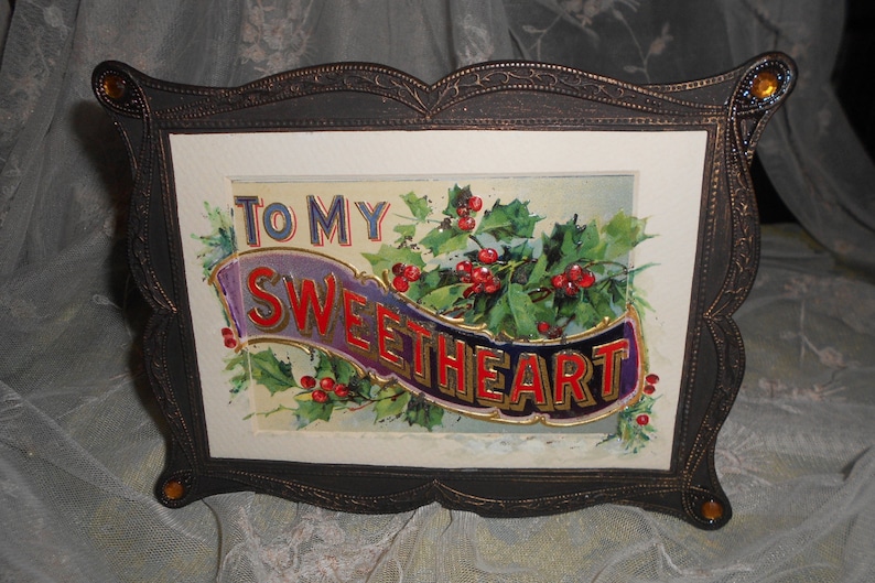 May include: A framed vintage postcard with a holly and berry design. The postcard reads "To My Sweetheart" in gold lettering on a purple and blue banner.