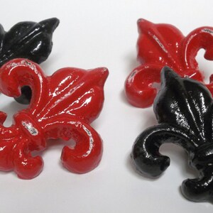 May include: Four decorative fleur-de-lis, two red and two black, with a distressed finish.