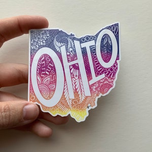 May include: A sticker in the shape of Ohio with a gradient design in shades of purple, pink, orange, and yellow. The word "OHIO" is in large white letters across the center. The design includes intricate patterns.