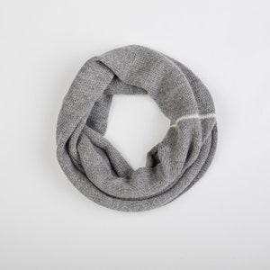 Könnte beinhalten: Ein grauer gestrickter Infinity-Schal mit einem weißen Streifen.