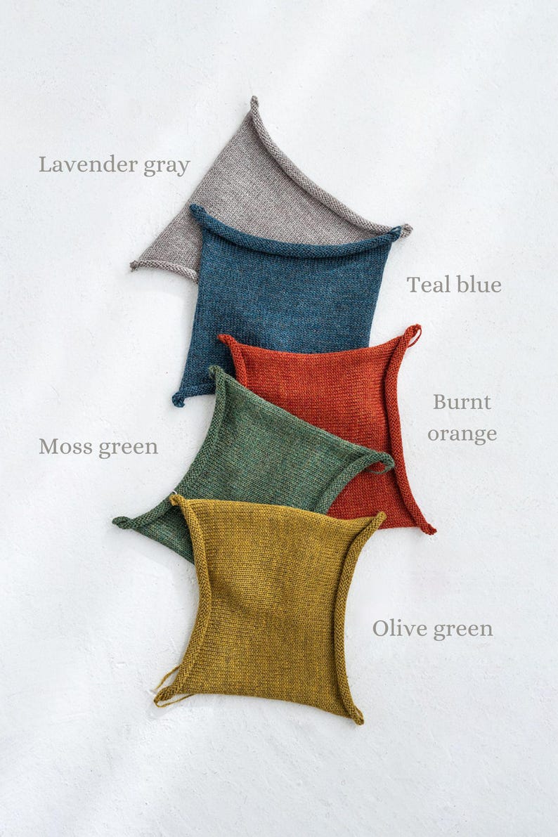 May include: Five knitted squares in different colors, stacked on top of each other. The colors are lavender gray, teal blue, burnt orange, moss green, and olive green.