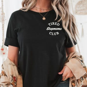 May include: Black t-shirt with white text that reads "Tired Stepmoms Club".