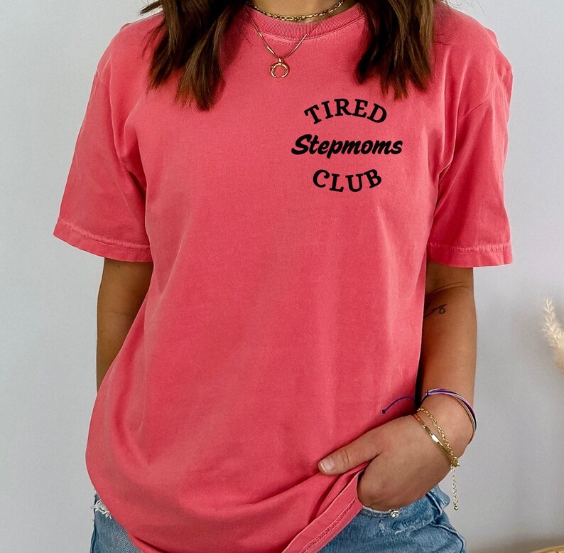 May include: A pink t-shirt with the text "TIRED Stepmoms CLUB" printed on the front.