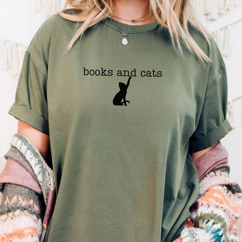 May include: A green t-shirt with the text "books and cats" and a silhouette of a cat reaching up printed on the front.