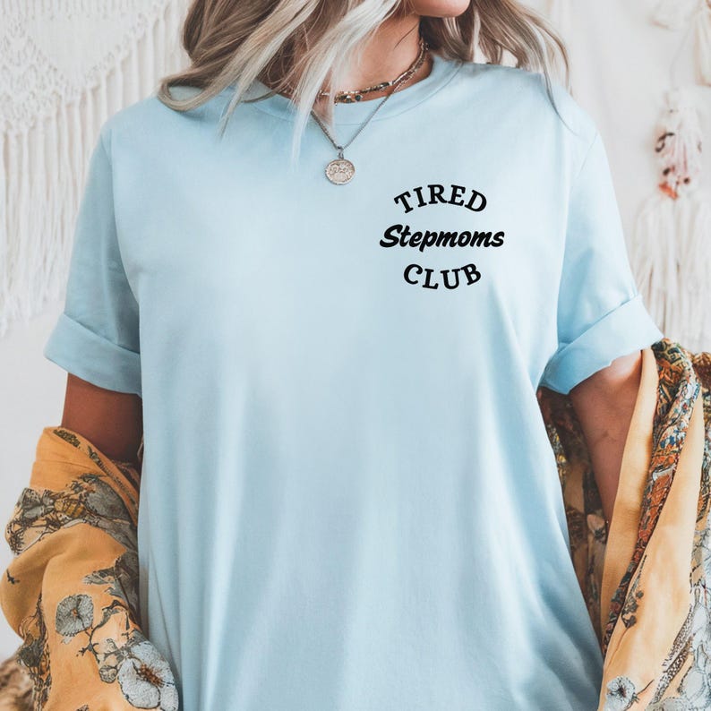 May include: Light blue t-shirt with the text "TIRED Stepmoms CLUB" in black.