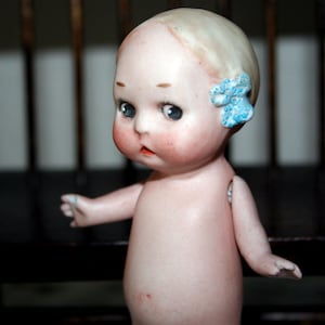 May include: A white ceramic mug with a black handle and the text "But First, Coffee" in a bold, black font. The mug is set against a blurred background, suggesting a cozy setting.