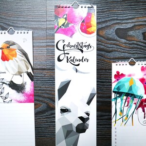 May include: Three different vertical wall calendars with colorful geometric animal illustrations. The calendars feature a robin, a llama, and a jellyfish. The calendars are titled "Geburtstagskalender" which translates to "Birthday Calendar".