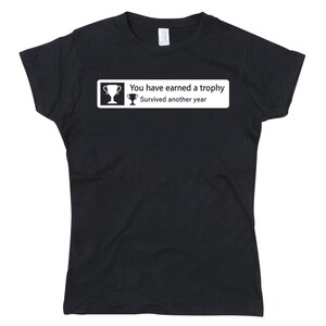 May include: Black t-shirt with a white graphic that says "You have earned a trophy. Survived another year." and a trophy icon.