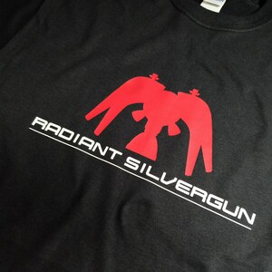 May include: Black t-shirt with a red graphic of a stylized eagle with the text "RADIANT SILVERGUN" in white.