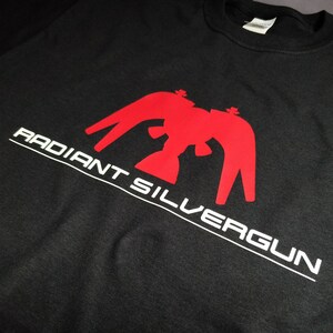 May include: Black t-shirt with a red eagle graphic and the text "RADIANT SILVERGUN" in white.