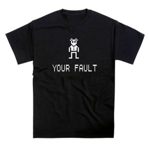 May include: Black t-shirt with a white pixelated figure and the text "YOUR FAULT" in white.
