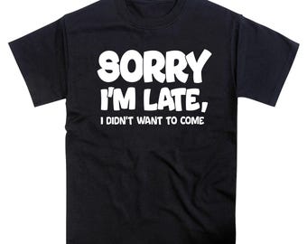 May include: A black short-sleeved t-shirt featuring white text printed on the chest that reads, "SORRY I'M LATE, I DIDN'T WANT TO COME." The shirt has a crew neckline and a standard fit, with the bold white lettering centered prominently on the front.