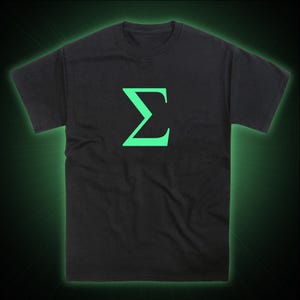 Op de afbeelding: Een zwart T-shirt met een groene, in het donker lichtgevende Griekse letter sigma, gedrukt op de voorkant.