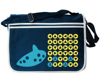 May include: A blue canvas messenger bag with a white trim. The bag features a yellow and blue graphic of a video game character's ocarina and a grid of yellow and blue triangles.