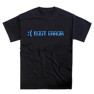 以下が含まれることがあります： 青い文字で「: ( BOOT ERROR」と書かれた黒いTシャツ。デザインは、単語の前に悲しい顔のシンボルがあり、テキストはピクセル化されたフォントです。シャツはクルーネックです。