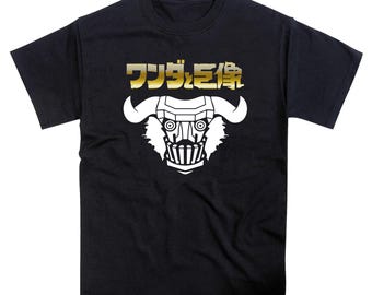 May include: Black t-shirt featuring a white graphic of a horned, masked figure with the Japanese text "Wonder Statue" in gold lettering across the top. The design is centered on the front of the shirt.