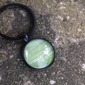 May include: A black key chain with a round green and white glitter charm.