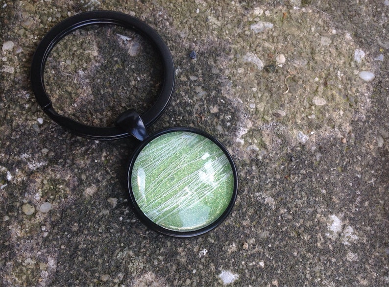 May include: A black key chain with a round green and white glitter charm.