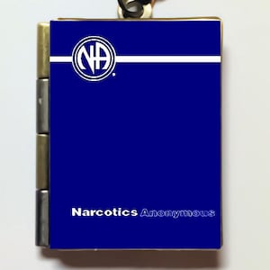Peut inclure: Un collier avec un médaillon bleu et blanc avec le logo de Narcotiques Anonymes et le texte "Narcotiques Anonymes".