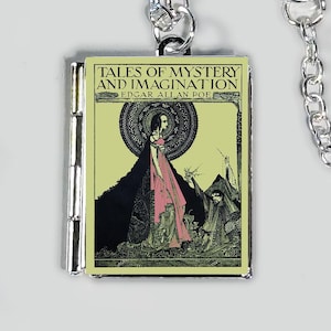 Puede incluir: Collar plateado con un colgante rectangular que muestra la portada de "Tales of Mystery and Imagination" de Edgar Allan Poe. El colgante muestra a una mujer con un vestido rosa y una capa negra, con el título del libro y el nombre del autor.