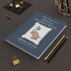 May include: A blue hardback book with the title "The Tale of Jemima Puddle-Duck" by Beatrix Potter. The book features an illustration of Jemima Puddle-Duck wearing a pink dress and a blue hat.