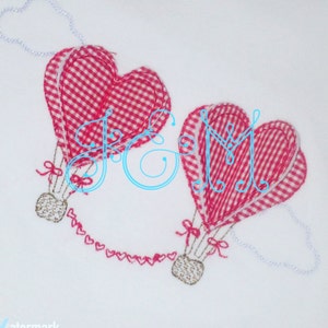 May include: Two red and white gingham heart-shaped hot air balloons with gold string details and a chain of small hearts connecting them.