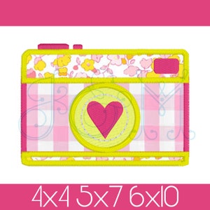 May include: A yellow and pink camera with a heart in the lens. The camera is decorated with a floral pattern and a checkered pattern. The text "4x4 5x7 6x10" is printed below the camera.