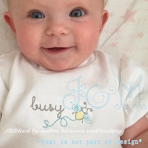 May include: A white onesie with blue embroidery of the letters "J & M" and a bee with the word "busy" above it. The text "Stitched by cotton blossom embroidery *text is not part of design*" is below the bee.