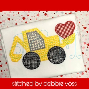 May include: A yellow toy construction vehicle with a red and white checkered heart in the bucket. The vehicle has black tires and a gray and white patterned cab. The image is stitched with the text "stitched by debbie voss".