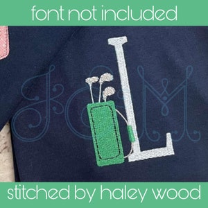 May include: A navy blue shirt with a white embroidered letter L and a green embroidered golf bag with golf clubs. The text "stitched by haley wood" is at the bottom of the image.