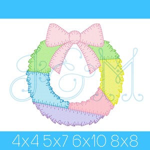 May include: A colorful, stitched wreath design with a pink bow at the top. The wreath is divided into sections of green, blue, purple, and yellow. The text at the bottom reads "4x4 5x7 6x10 8x8".