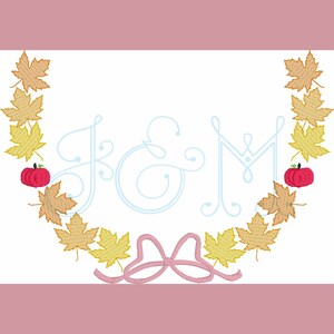 May include: A monogram with the letters "K & M" in a light blue script font, surrounded by a wreath of orange and yellow maple leaves with red pumpkins. A pink bow is at the bottom of the design.
