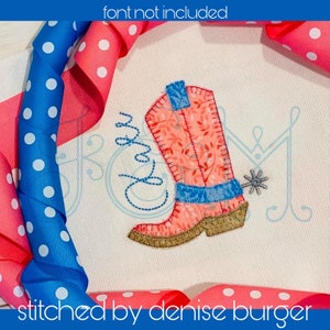 May include: A pink and blue embroidered cowboy boot with a spur. The boot is stitched on a white fabric background. The text "stitched by denise burger" is at the bottom of the image.