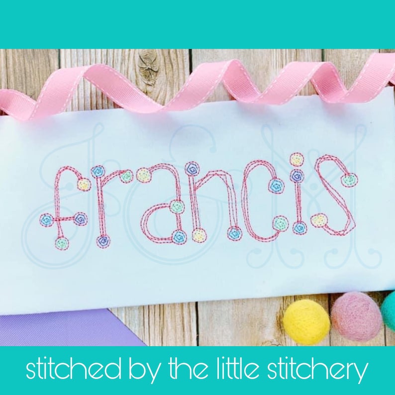 May include: Embroidered name "Francis" in pink thread with colorful dots on a white fabric background. The name is stitched in a cursive font.