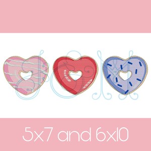 Op de afbeelding: Drie hartvormige donuts met verschillende gekleurde glazuur en sprinkles. De donuts zijn roze met witte strepen, rood met witte strepen en blauw met blauwe sprinkles. De tekst "5x7 en 6x10" staat onder de donuts.