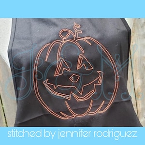 May include: A black fabric apron with an orange embroidered jack-o'-lantern design. The design is stitched with a detailed outline of a pumpkin with a carved face.