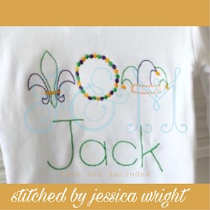 Peut inclure: Broderie représentant un lys, des perles et une couronne, avec le nom "Jack" brodé en fil vert. Le texte "text not included" est également visible sous le nom.