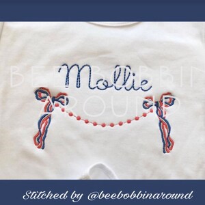 May include: White onesie with the name "Mollie" embroidered in blue thread.  Two red and blue bows are stitched on either side of the name with a string of red beads connecting them.  The text "Stitched by @beeboppinaround" is at the bottom of the onesie.
