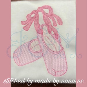Puede incluir: Zapatillas de ballet bordadas en rosa con una cinta rosa atada alrededor. Las zapatillas están cosidas sobre un fondo de tela blanca.