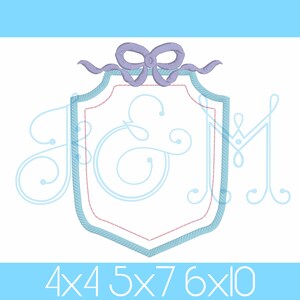 Könnte beinhalten: Ein blaues und weißes Monogramm-Stickmuster mit einer lila Schleife oben. Das Design zeigt die Buchstaben "J & M" in einer dekorativen Schreibschrift. Das Design ist in vier Größen erhältlich: 4x4, 5x7, 6x10.