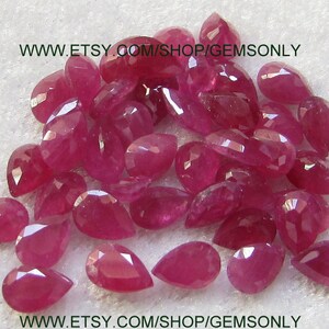 Peut inclure: Un tas de pierres précieuses rubis en forme de poire, toutes d'une couleur rose foncé. Les pierres précieuses sont disposées en un tas lâche sur une surface blanche. Le texte "www.etsy.com/shop/gemsonly" est visible en bas de l'image.