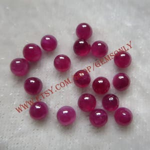 Puede incluir: Una colección de 18 piedras preciosas redondas de rubí rojo. Las piedras preciosas son de varios tamaños y están dispersas sobre una superficie blanca. El texto "WWW.ETSY.COM/SHOP/GEMSONLY" es visible en la imagen.